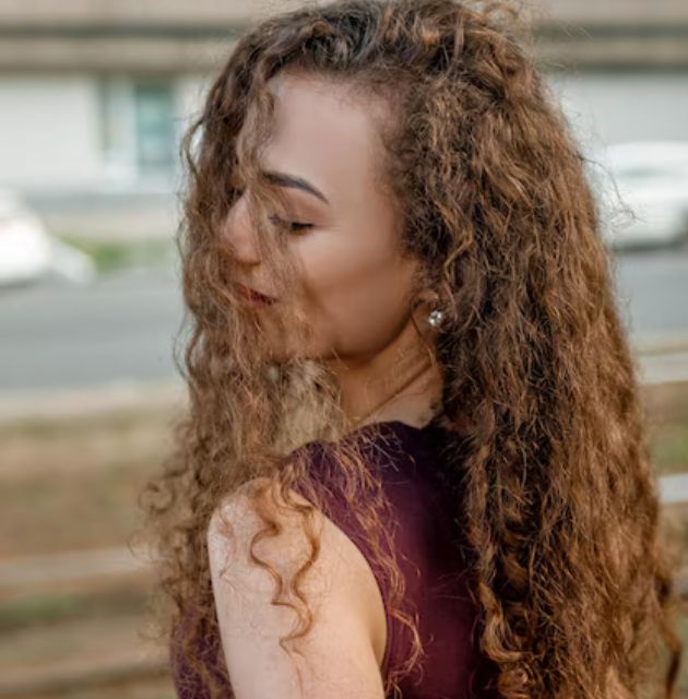 "Bridal hairstyle for short curly hair with boho waves, offering a relaxed and effortlessly stylish look for your special day."







