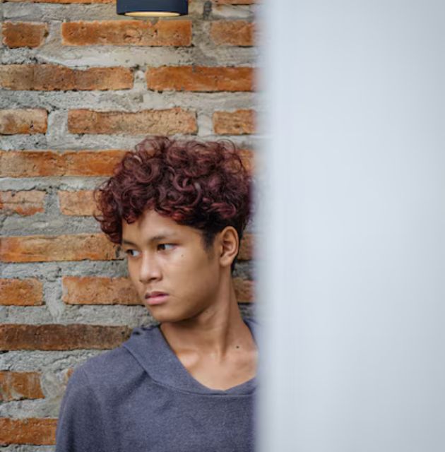 "Undercut for men's short curly haircuts, featuring a bold contrast between closely shaved sides and fuller curls on top, creating a modern and edgy look."