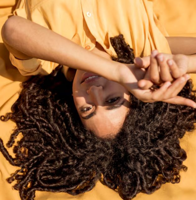 "Person brushing through curly hair, releasing shed hair strands."